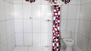 A bathroom with white tiled walls and floor, a shower with a white door, and a toilet.