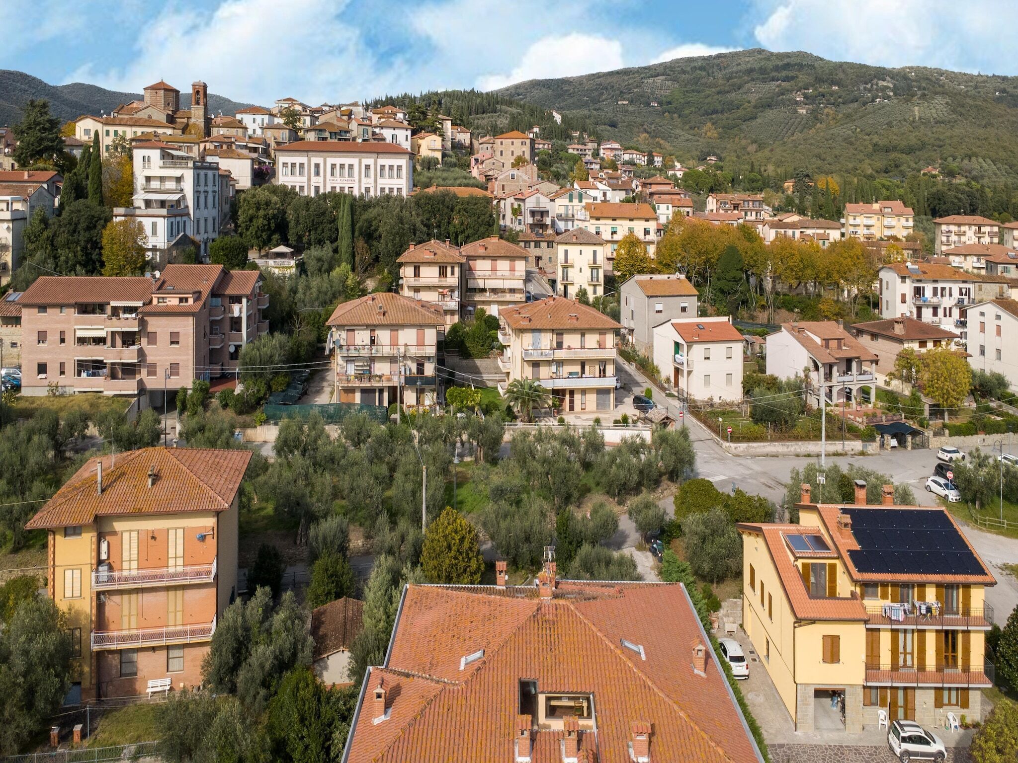 Un barrio residencial con edificios de varios pisos, algunos con balcones, y un terreno montañoso de fondo.