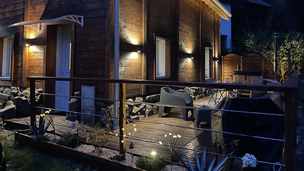 Une cabane en bois dotée d’une terrasse, d’un espace salon extérieur et d’un mur en pierre.