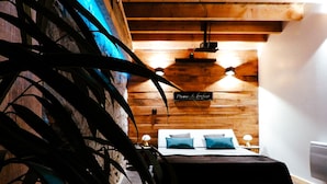 Une chambre avec un plafond en bois, un lit recouvert d’une courtepointe noire et une pancarte sur laquelle on peut lire « Plaza de la Luna ».