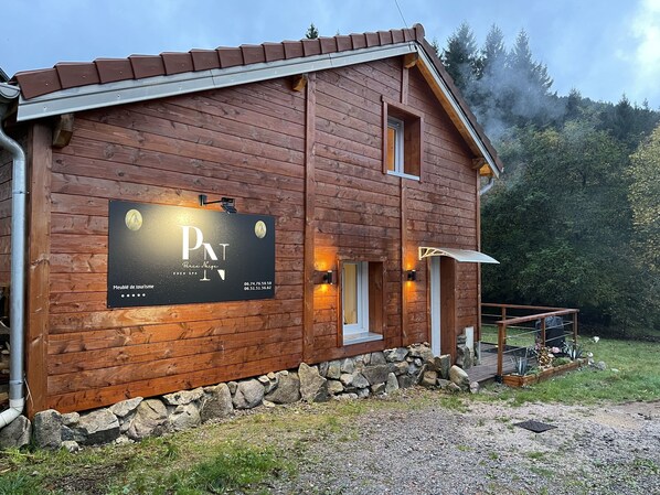 Un bâtiment en bois sur lequel est apposée une enseigne indiquant qu’il s’agit d’un établissement touristique.
