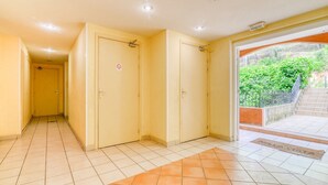 A hallway with a tiled floor, a door with a no-smoking sign, and a view of greenery outside. - Mougins Hideaway for 4 Guests (Mougins)