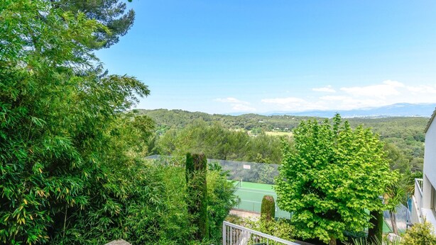 A residential area with a tennis court, lush greenery, and a view of distant hills. - Mougins Hideaway for 4 Guests (Mougins)