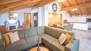 A cozy living room with a sectional sofa, a dining area, and a kitchen. - Luxury penthouse in Brixen im Thale (Brixen im Thale)
