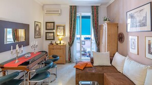 A living room with a dining table, chairs, a sofa, and a view through a glass door to an outdoor balcony. - Apartment in Rome with balcony (Roma)
