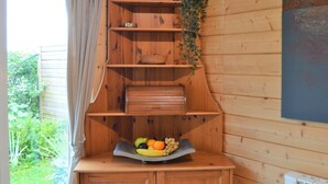 Un intérieur en bois avec une bibliothèque intégrée, une petite table sur laquelle sont disposés des fruits et une plante en pot.