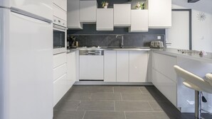 A modern kitchen with white cabinetry, a built-in oven, a dishwasher, and a stainless steel sink.