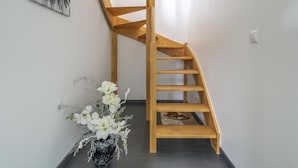 A wooden spiral staircase in a room with a white wall and a black floor.