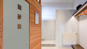 Ein modernes Badezimmer mit Holztür, einer gefliesten Duschkabine und einer eingebauten Sitzbank.