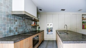 Eine moderne Küche mit Holzausstattung, einer schwarzen Arbeitsfläche und einem eingebauten Ofen.