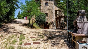 Un edificio de piedra de aspecto rústico, un sendero de grava que lo conduce y una estructura similar a una chimenea a la derecha.