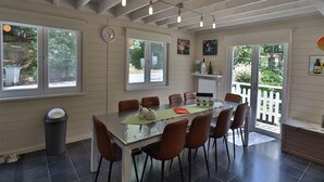 A dining area with a large table, chairs, and a clock on the wall. - Stylish Chalet with Room (Durbuy)