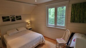 A bedroom with a bed, a chair, a nightstand, a window, and a painting. - Stylish Chalet with Room (Durbuy)