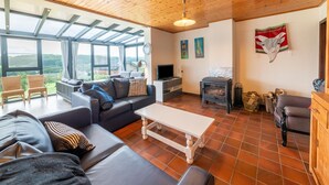 Una sala de estar moderna con sofá, mesa de centro y chimenea. Hay ventanas amplias y vistas al exterior.
