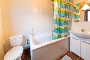 A bathroom with a toilet, bathtub, and sink.