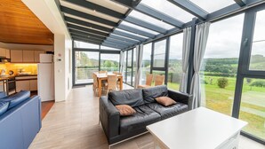 Un interior moderno con cocina, comedor y zona de estar, con ventanas amplias.