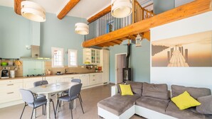 A spacious living area with a large sectional sofa, a dining table with chairs, and a kitchen in the background.