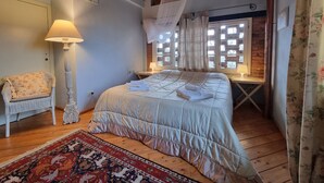 A bedroom with a bed, a chair, a lamp, a window with curtains, and a wooden ceiling. - Farmhouse in Tuscany with Pool near Montecastello (Toscana)