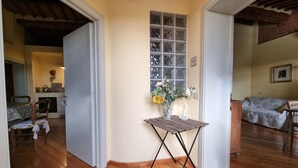 A room with wooden flooring, a dining table with chairs, a kitchen area with a stove, and a window with a view of the outside. - Farmhouse in Tuscany with Pool near Montecastello (Toscana)