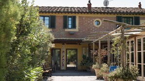 A building with a tiled roof, a brick facade, and a covered entrance area with potted plants. - Farmhouse in Tuscany with Pool near Montecastello (Toscana)