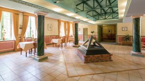 Un'ampia hall con soffitti alti, grandi finestre e un camino centrale.