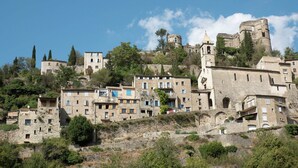 Un borgo storico con edifici in pietra, una torre imponente e un castello su una collina.