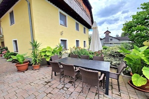 Une terrasse extérieure avec une table et des chaises, entourée de plantes en pot.