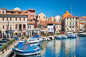 A waterfront area with boats docked, buildings with balconies, and a clear blue sky.