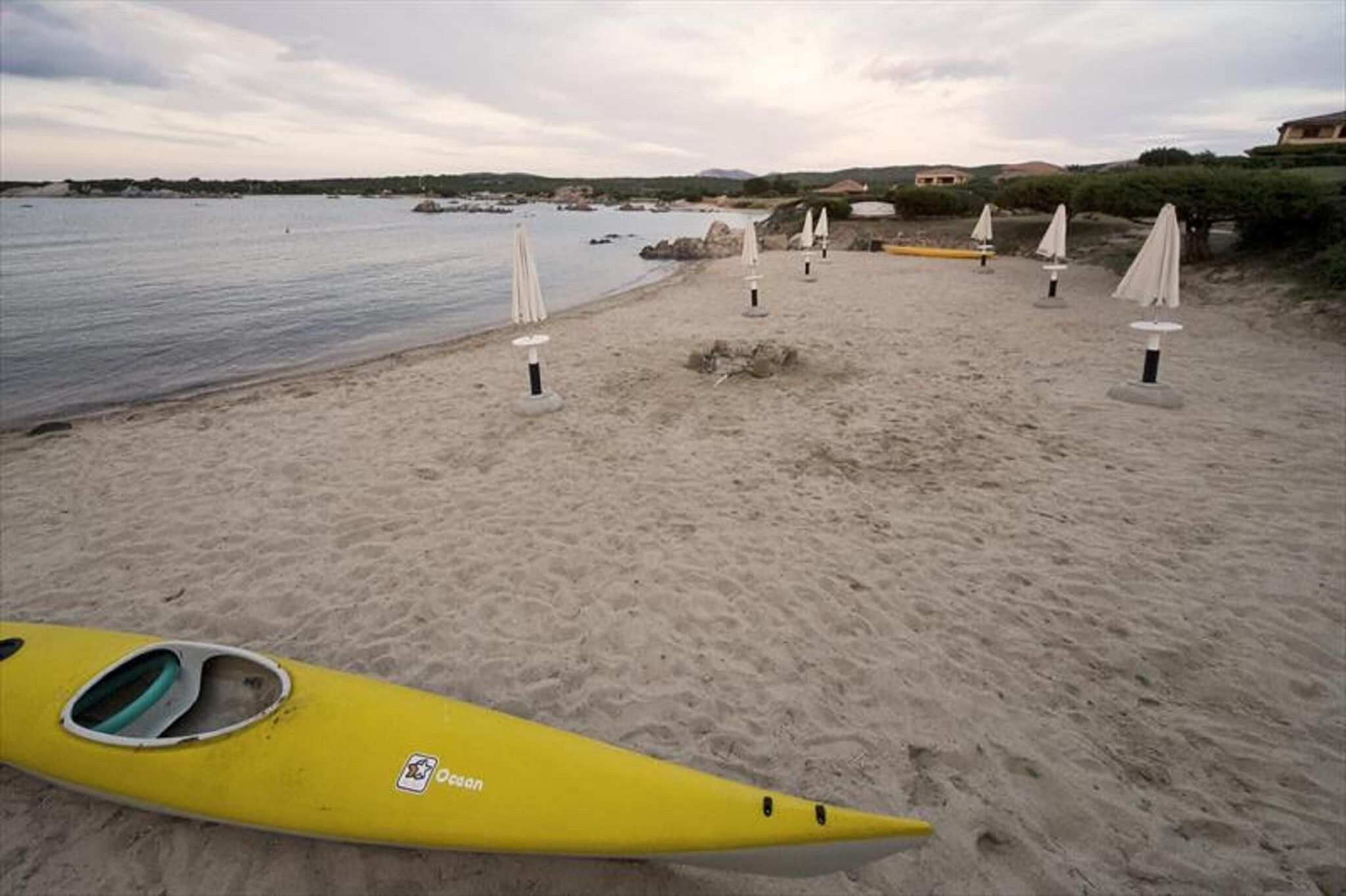 Une plage avec des kayaks et des parasols.