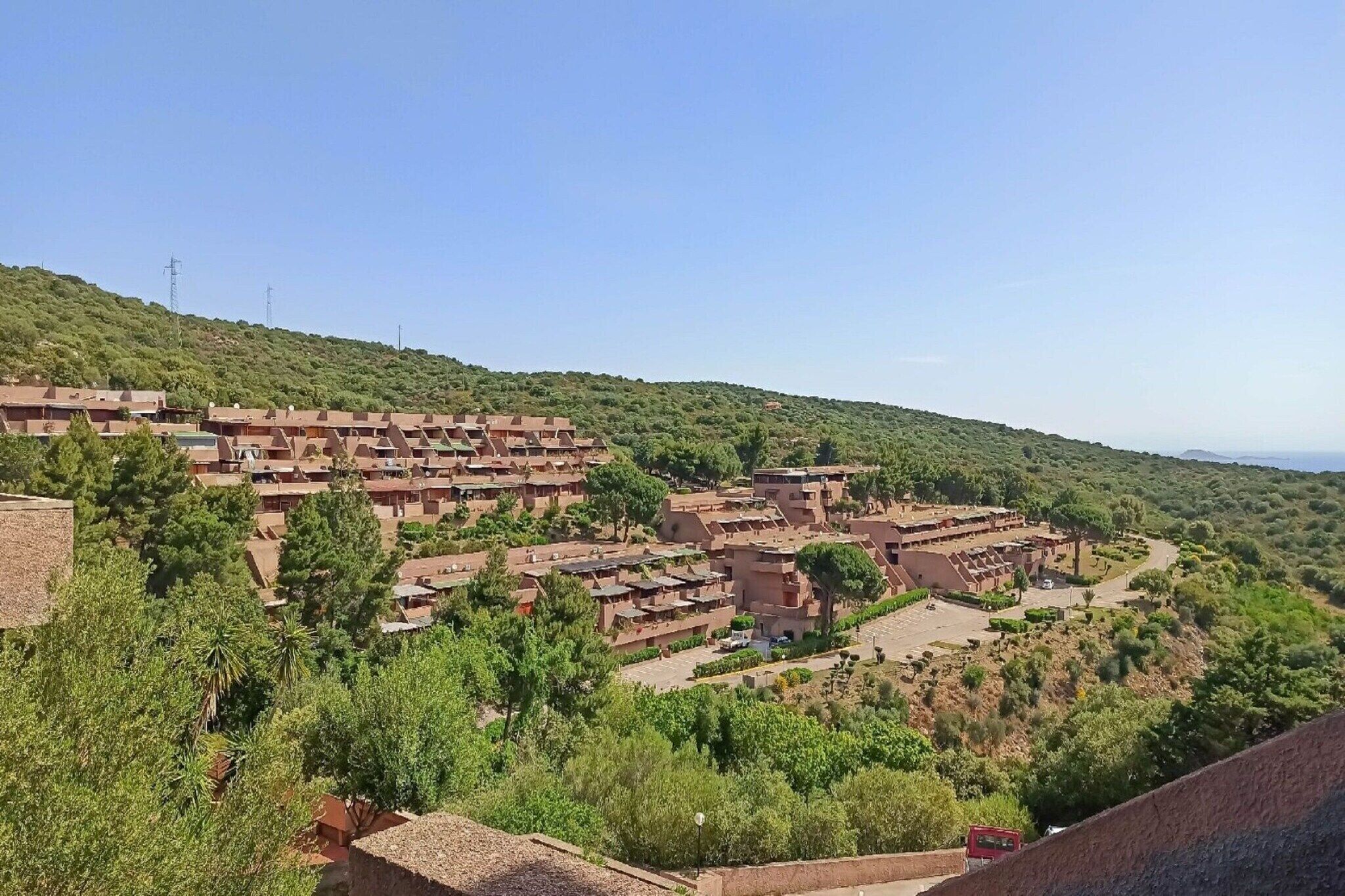 Un pueblo en una ladera con edificios escalonados y abundante vegetación.
