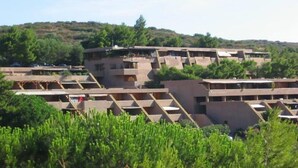 A multi-story building with a flat roof and a series of balconies.