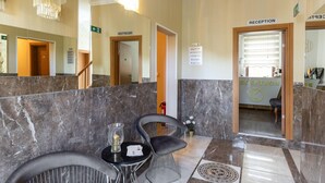Ett välkomstområde med marmorgolv, en receptionsdisk och en stol.