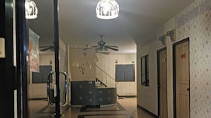 Ein Hotelkorridor mit einer zentralen Treppe, Deckenventilator und Wandverkleidung mit Muster.
