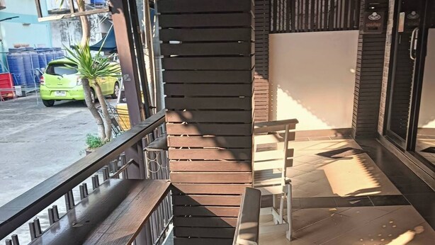 Ein überdachter Außenbereich mit Holzbänken und -tischen, einer Treppe und Blick auf die Straße.