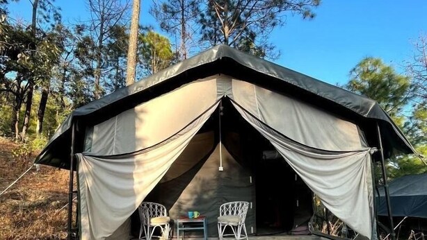 Uma tenda com uma escadaria de pedra que leva até ela, duas cadeiras brancas e uma mesa na frente.
