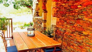 A wooden table with metal chairs, a lantern, and a stone wall. - Magnificent cottage in Payzac with pool ! (PAYZAC)