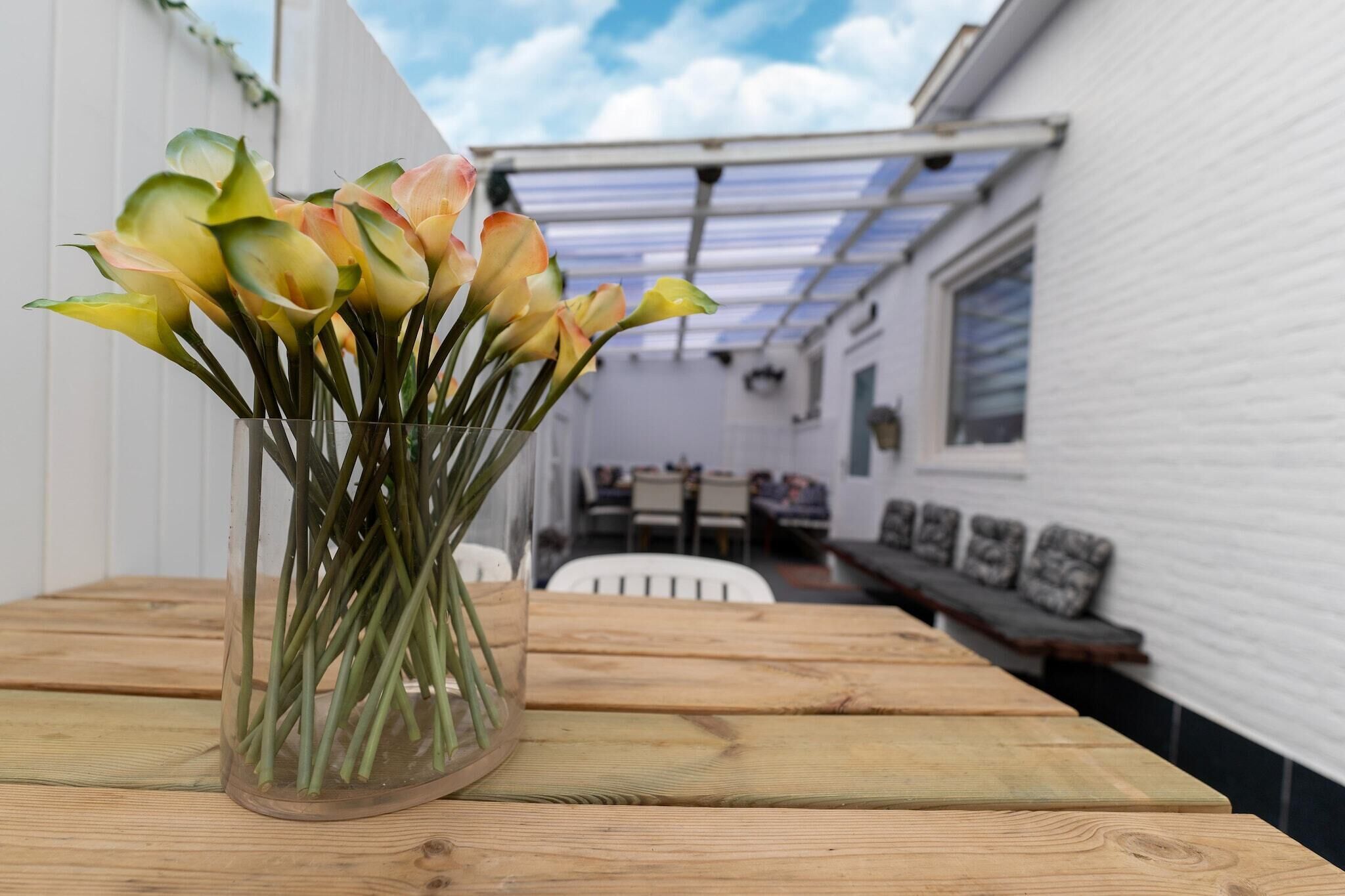 A wooden table with a glass vase containing flowers.