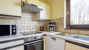 A kitchen with a microwave, oven, dishwasher, and coffee maker. - Holiday home Les Hirondelle for 8 persons (Bievre)