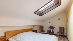 A bedroom with a skylight, a bed, two chairs, a nightstand, and a small table with a vase of flowers. - Holiday home Les Hirondelle for 8 persons (Bievre)