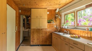 Cocina compacta con armarios de madera, un lavamanos y una ventana con vistas a flores.