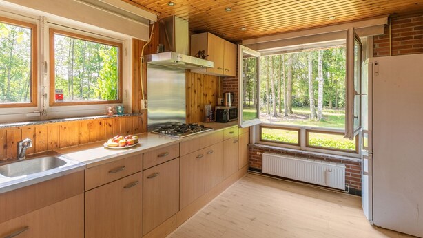 Una cocina moderna con armarios de madera, una estufa de acero inoxidable y un ventanal con vistas al exterior.