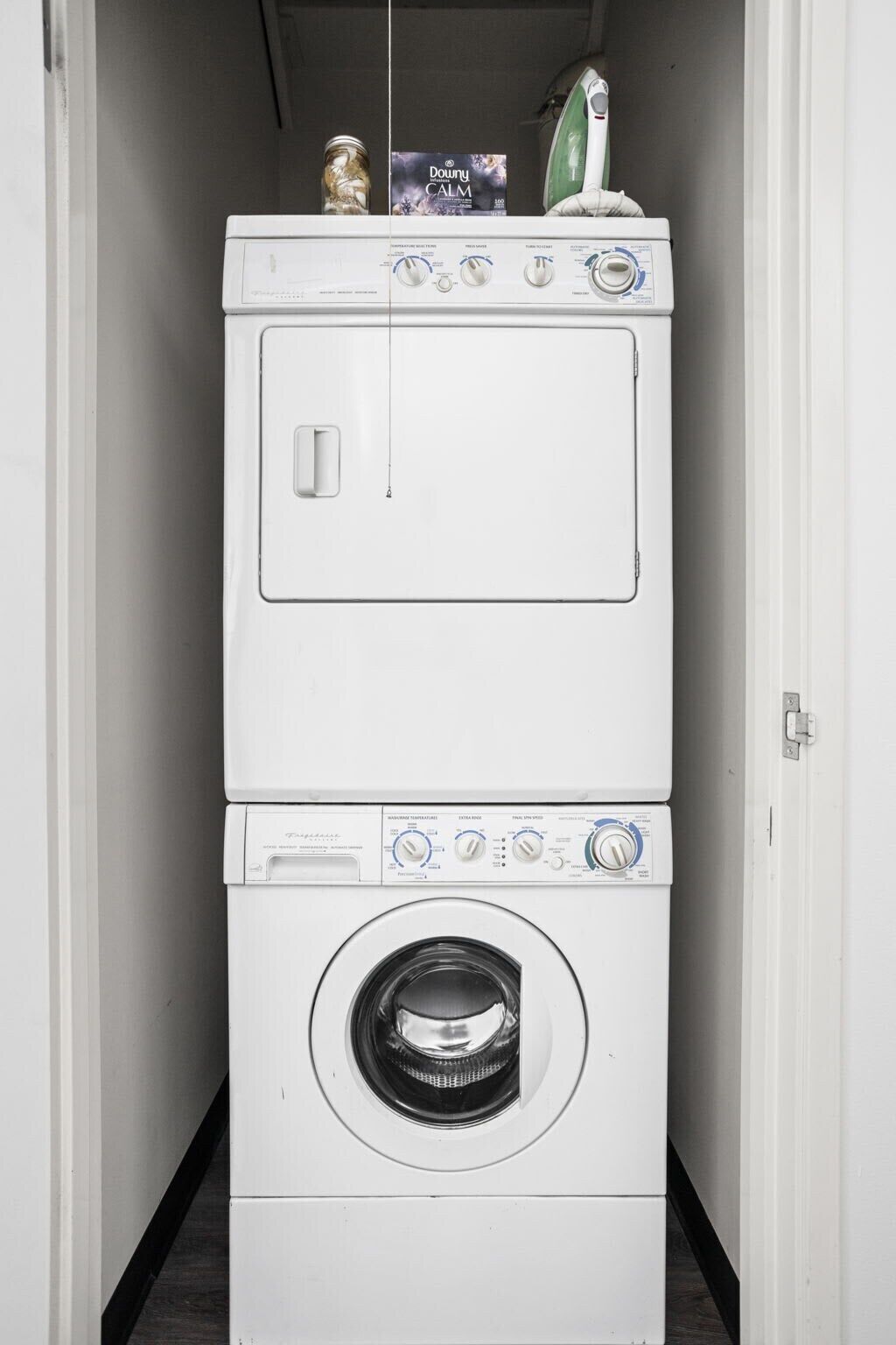 Un appareil compact, blanc, combinant une machine à laver et un sèche-linge à chargement frontal, doté d’un panneau de commande et d’une seule porte.