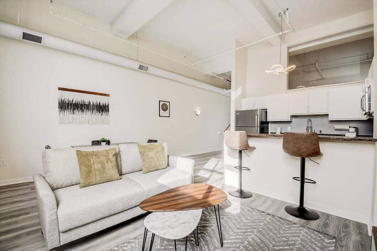 A modern living room with a sofa, coffee table, and a bar area with stools.