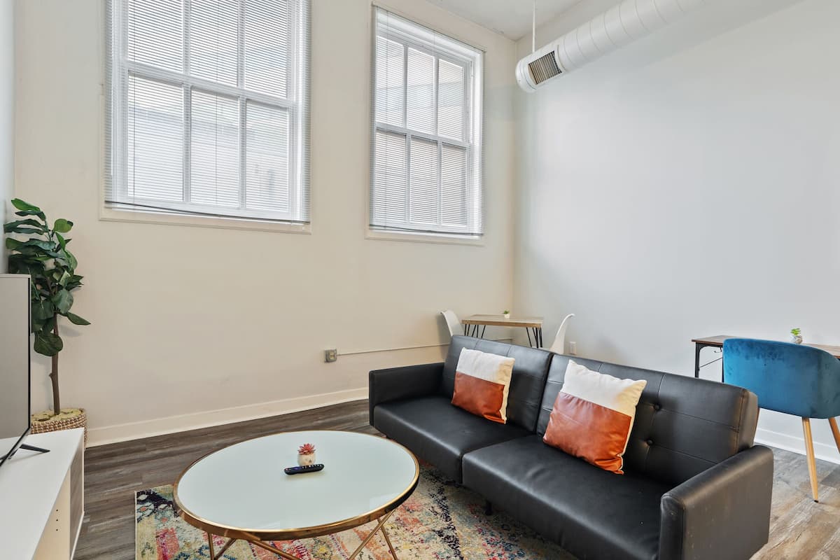 A modern living room with a black leather sofa, a round coffee table, and a small side table.
