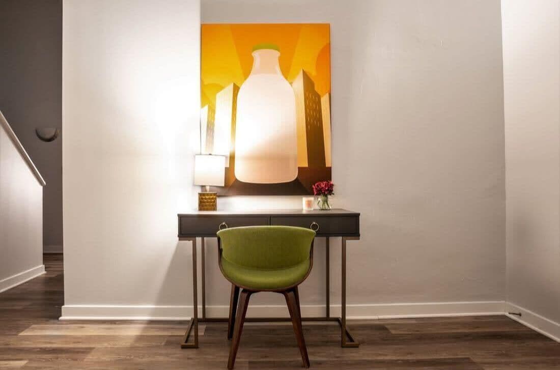 Ein modernes Interieur mit Schreibtisch, Stuhl und einem Gemälde an der Wand.