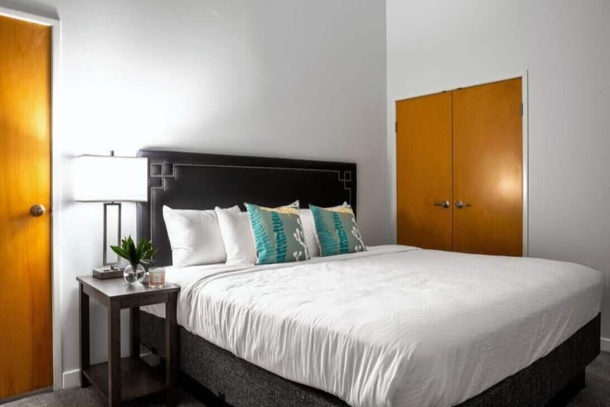 A hotel room with a large bed, a bedside table with a lamp, and a wardrobe.