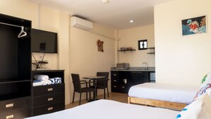 Une chambre d’hôtel avec deux lits, un bureau avec une chaise, une petite kitchenette et un téléviseur.
