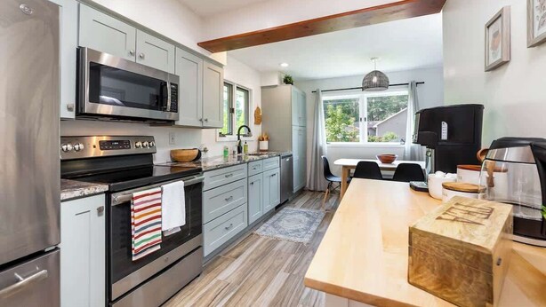 A modern kitchen with stainless steel appliances, a wooden island, and a view of the outdoors.