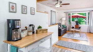 A modern kitchen with a coffee maker, storage jars, and a wooden counter.