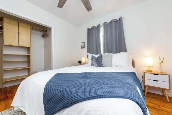 A bedroom with a bed, a wardrobe, a nightstand, and a window with curtains. - Urban Gem: Mins to Beach & Downtown + Hot tub! (Traverse City)